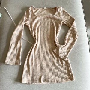 Beige ribbad långärmad klänning - Säljer en beige ribbad klänning med lång ärm och fyrkantig ringning. Klänningen är figurnära och har en mjuk, stretchig känsla. Perfekt för dig som gillar enkel och stilren design.