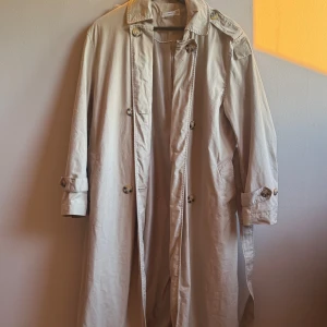 Trenchcoat beige - I superfint skick. Ganska stor i storleken så passar även en s.