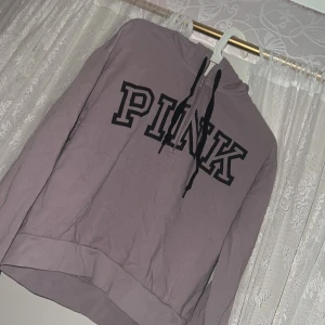 Ljuslila hoodie från Victoria secret PINK - Säljer en ljuslila hoodie från PINK med svart tryck framtill och svarta dragsnören i huvan. Tröjan har lång ärm och en klassisk hoodie-passform. Perfekt för en avslappnad stil.