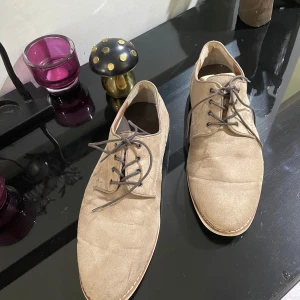 Beige snörskor från H&M - Säljer ett par stilrena beige snörskor från H&M med rund tå och platt sula. Skorna har ovandel i syntetmaterial mocka  . Perfekta för en clean och enkel look.storlek 42.kan möta er i Stockholm 