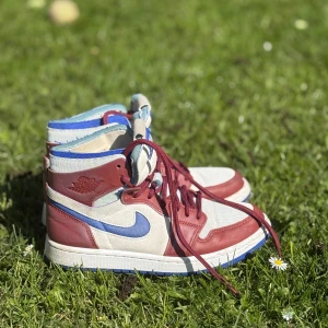 Nike Air Jordan 1 Zoom Air i rött, blått och vitt - Säljer ett par Nike Air Jordan 1 Zoom Air med röd och vit ovandel, blå detaljer och sula. Skorna har högt skaft, snörning och klassisk Jordan-logga på sidan. Använda mellan 5-10 gånger!💫