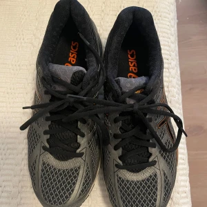 ASICS Gel-Cumulus 17 Löparskor - Grå/Orange - EUR 40.5 - Bekväma löparskor från ASICS, modell Gel-Cumulus 17. Skorna har en dämpande mellansula och en yttersula med bra grepp. Perfekt för löpning på olika underlag. Designen ger en lättare studs tack vare FluidRide 2.0-tekniken med vilken mellansulan är förstärkt. SpEVA 45-tekniken ger dig ett starkare fotfäste. Yttersulans djupa spår ger din fot riktning. Varje landning blir mjukare tack vare stötdämpningen av GEL-material fram och bak.  Väldigt lite använda så i bra skick.