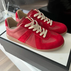 Röda sneakers från maison margiella  - Säljer ett par snygga röda maison margiella skor perfekt inför sommarn och riktigt feta, och helt nya. Jag säljer dom för att jag råkade köpa fel storlek, pris kan diskuteras. Maison margiella boxen ingår!!