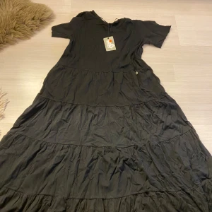 Svart långklänning från Ajlajk - Säljer en svart långklänning från Ajlajk med korta ärmar . Klänningen har en avslappnad passform och är tillverkad i ett mjukt material som känns skönt mot huden. Perfekt för dig som gillar en enkel men stilren look.