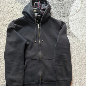 Svart Burberry hoodie  - Säljer nu denna Svarta Burberry zip up hoodien då jag inte längre har användning av den, storleken är Large men sitter som en Medium. Skick - 8/10