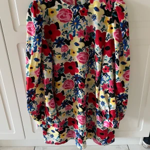 Blommig långärmad klänning från NA-KD - Färgglad klänning med blommigt mönster i rött, rosa, blått och gult i storlek 38 