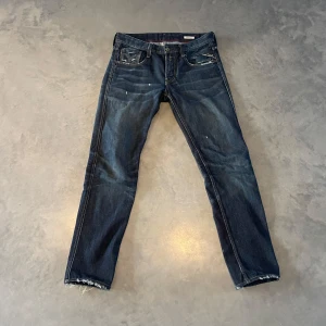Mörkblå Replay Anbass jeans - Säljer ett par mörkblå Replay Anbass jeans med klassisk femficksdesign och snygga slitningar. Storlek 30 i midjan och 34 i längden. Märkespatch bak i midjan och diskreta detaljer vid fickorna. Väldigt lätta att styla! Hör av er om ni har några funderingar! 