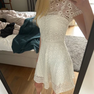 Vit spetsklänning med kort ärm - Säljer en söt vit klänning med korta ärmar och rund hals. Klänningen är täckt av broderad spets med cirkelmönster och har en lätt utställd kjol. Perfekt till t.ex. student eller skolavslutning💗💗