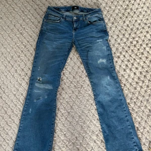 LTB jeans - Säljer ett par blå bootcut jeans från LTB, modell ROXY. Jeansen har klassisk femficksdesign, dragkedja och knapp framtill samt lätt slitna detaljer på framsidan. Perfekta för dig som gillar en tidlös jeanslook. Har dock en liten slitning vid baksida häl, men inget man tänker på!