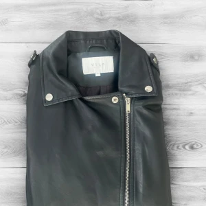 Svart skinnjacka från Vila - Säljer en svart skinnjacka från Vila med klassisk bikerstil. Jackan har sned dragkedja, silverfärgade detaljer och två fickor med dragkedja framtill. Perfekt för dig som vill ha en tidlös och snygg jacka till garderoben.Helt ny endast testad! Nypris kostar den 600 men släpper den för 249. Hör av dig vid funderingar✅ 