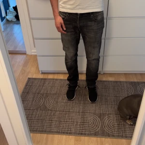Svarta jeans från Jack & Jones - Säljer ett par svarta jeans från Jack & Jones i storlek 32. De har en snygg, sliten look och är i bra skick. Perfekta för både vardag och fest! 