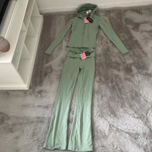 Grön hoodie med matchande byxor från PrettyLittleThing - Säljer denna superstretchiga och bekväma yoga-dress från PrettyLittleThing i färgen sage green. Tyvärr beställde jag fel storlek för mig, så den är helt oanvänd med lapp kvar – endast testad!  ✅ Storlek: XXS ✅ Färg: Sage green (ljus/mjuk grön ton) ✅ Material: Stretchigt och följsamt – perfekt för yoga, träning eller lounging ✅ Skick: Ny, aldrig använd bara testad!  Perfekt för dig som vill ha en snygg och bekväm träningsdress i sommar! 💚  💌 Skriv vid frågor eller om du är intresserad!