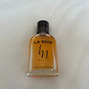 La Rive In Woman Eau de Parfum - En elegant parfym för kvinnor från La Rive. Luktar sommar - ger en varm och fyllig doft. Mer än halva flaskan kvar. Säljer samma på vinted så kontakta gärna innan ni trycker på ”köp”!