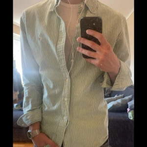Grön- och vitrandig skjorta från Polo Ralph Lauren - Säljer en randig skjorta från Polo Ralph Lauren då den är för stor på mig som brukar ha storlek S-M. Skjortan är slim fit i storlek L vilket den passar som. Nypris ca 1600kr. Hör av er vid frågor, pris kan diskuteras vid snabb affär!