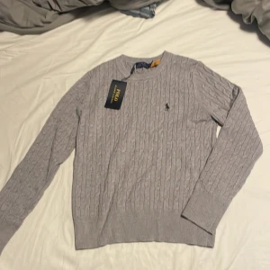 Ljusgrå kabelstickad tröja från Polo Ralph Lauren - Hej! Jag säljer denna kabelstickade polo tröjan som var för liten för mig. Väldigt skönt bomullsmatrial som e perfekt nu till sommaren. Priset kan diskuteras!