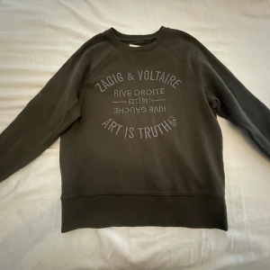 Mörkgrön sweatshirt från Zadig & Voltaire - Cool mörkgrön sweatshirt från Zadig & Voltaire med tryck på bröstet. Tröjan har rund halsringning och långa ärmar. Perfekt för en avslappnad stil och enkel att matcha med jeans eller joggers.