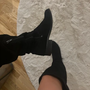 Svarta höga stövlar med dragkedja - Säljer ett par svarta höga stövlar med dragkedja på sidan. Låg klack  i mocka.  Storlek 39 passar mig som vanligtvis har 38a, som nya!