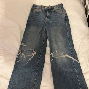 Blå slitna jeans från g perfect jeans - Säljer ett par blå jeans från g perfect jeans i storlek 34. Jeansen har raka ben och slitna detaljer med hål på båda knäna. Klassisk femficksmodell och normal passform. Perfekta för en avslappnad och trendig look. Syns knappt att de varit i bruk men använda mer än 5 gånger därav billiga priset. Inköpspris 300 kr