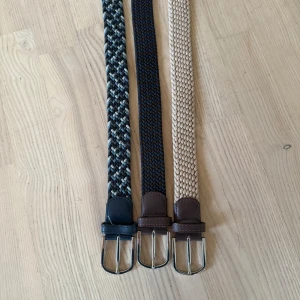 Tre flätade bälten med skinnspänne  - Säljer tre snygga flätade bälten i olika färger. Ett är svart/grå/vitt med svart skinn, ett är blå/brunt med brunt skinn och ett är beige med brunt skinn. Alla har silverfärgat spänne och är i storlek 110/43. Ett par för 299. Dm för frågor!