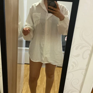 Vit oversized skjorta - Säljer en vit oversized skjorta med klassisk krage och stora bröstfickor. Skjortan har långa ärmar och knäppning framtill. Perfekt för en avslappnad och trendig look.