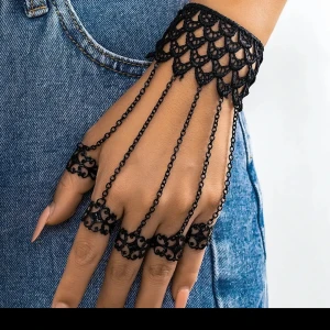  Helt ny Svart spetsarmband med kedjor och ringar - Unikt svart armband i spets med dekorativa kedjor som fästs runt varje finger som ringar. Ger en cool och elegant look, perfekt för att sticka ut. Spetsmönstret har en vintagekänsla och kedjorna ger extra edge.