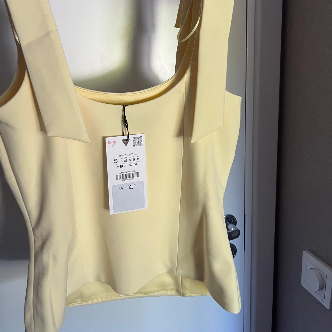 Ljusgul topp med rosetter på axelbanden - 1