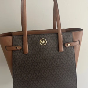Äkta väska ifrån Michael kors - Säljer denna jätte snygga axelväska ifrån micheal kors. Aldrig använd och har lappen kvar. Den är alltså i nyskick. Ger outfiten en lyxig touch och man får plats med massor i den. Nypris är ca 3000kr.