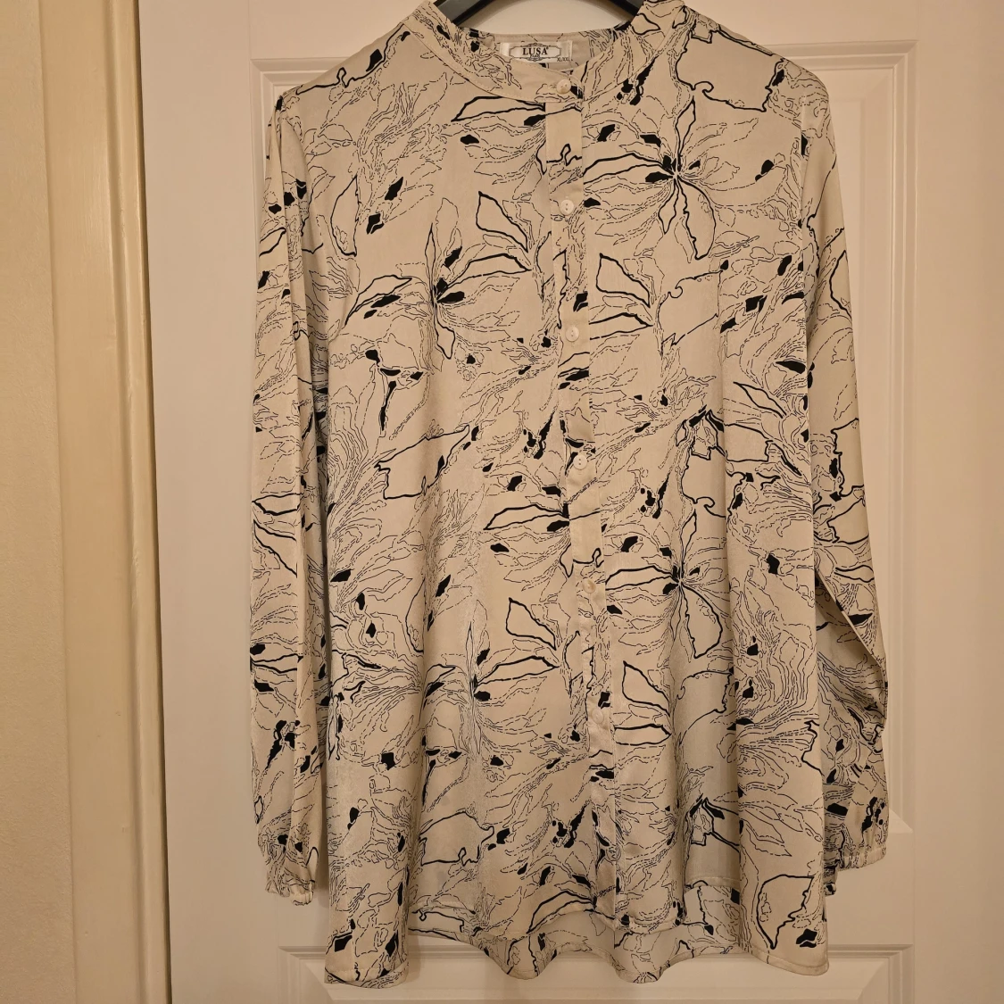 Vit blus med svart blommigt mönster