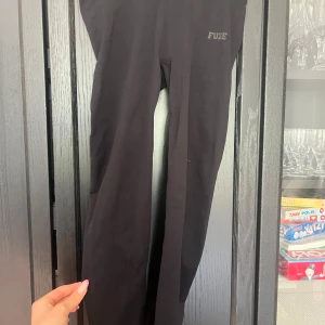 Svarta leggings från Fuze - Svarta leggings från Fuze med tight passform och scrunch-detalj bak. Mjukt och stretchigt material som sitter skönt på kroppen. Perfekta för träning eller en avslappnad look.