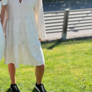 Vit broderad klänning med v-ringning - Superfin vit klänning från Moss Copenhagen med v-ringning och broderade detaljer. Klänningen har trekvartsärm och är tillverkad i bomull med ett luftigt, lätt material. Perfekt för varma dagar och har en avslappnad passform.