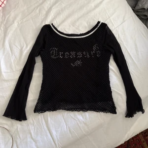 Svart meshtröja  - Säljer en svart y2k vintage långärmad meshtröja från Check This med nätmönster och tryck framtill. Tröjan har mesh see through ärmar och en silver detalj vid halsringningen. Perfekt för en edgy stil! #y2k 
