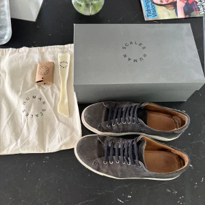 Marinblå sneakers från Humanscales - Säljer ett par marinblå sneakers från Humanscales med vita sulor och bruna detaljer på insidan. Skorna har snörning och rund tå, tillverkade i mocka med en klassisk och stilren design. Perfekta för dig som gillar minimalistiska och snygga skor. Lite slitna inuti skon. Box, skohorn, påse och nya skosnören medföljer. Nypris:2000kr. Pris ej hugget i sten! Ge prisförslag.