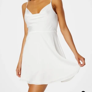 Kort vit satin klänning med smala axelband - Säljer en stilren vit kortklänning med smala axelband och lätt draperad urringning. Perfekt för sommarens alla tillfällen!