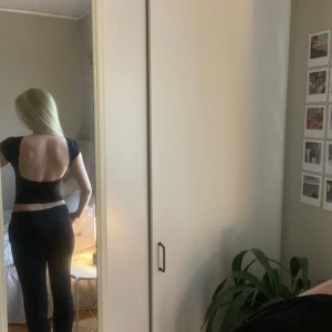Svart croppad topp med öppen rygg - Säljer en svart croppad topp med korta ärmar och snyggt öppen rygg. Toppen har en tight passform och är perfekt för att skapa en stilren look. Passar till många olika outfits och är enkel att matcha.