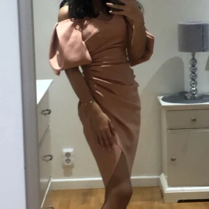 Rosa one shoulder klänning - Säljer en snygg rosa one shoulder klänning med volangdetalj på axeln och omlottkjol med slits. Perfekt för dig som vill sticka ut på festen! Klänningen har en tight passform och markerad midja.Pris går att diskutera 