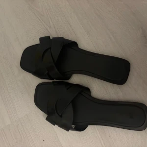 Svarta sandaler med flätad rem - Säljer ett par stilrena svarta sandaler med breda, flätade remmar och fyrkantig tå. Perfekta för varma dagar och enkla att matcha med olika outfits. Storlek 41 men är mer som 39/40! Aldrig använda