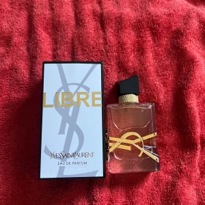 Yves Saint Laurent Libre Eau de Parfum - Säljer en lyxig parfym, Libre Eau de Parfum från Yves Saint Laurent. Flaskan är transparent med guldiga detaljer och svart kork, och kommer med originalkartong. Doften är modern och elegant med inslag av lavendel och apelsinblomma.