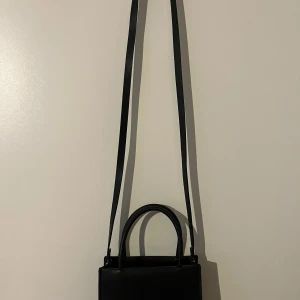 Svart axelväska i minimalistisk design  - Säljer en svart axelväska som även är en handväska. Den är från Kappahl🩷