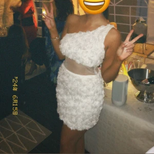 Vit axelbandslös klänning med rosdetaljer - Säljer en vit axelbandslös klänning med vackra rosdetaljer och transparent midjeparti. Perfekt för festliga tillfällen! Även suuuper nu till student tider! 🥹😍Endast använt en gång! 