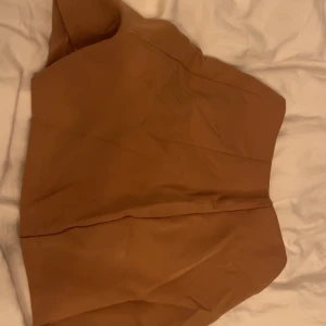 Beige kortkjol med slits - Trendig beige kortkjol med en stilren slits framtill. Perfekt för en chic och modern look. Kjolen har en enkel design som gör den lätt att matcha med olika toppar. Det är shorts inuti