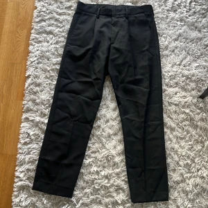 Svarta kostymbyxor från NN07 - Snygga svarta kostymbyxor från NN07. De har en klassisk design med raka ben och midwaist. Perfekta för en stilren look.