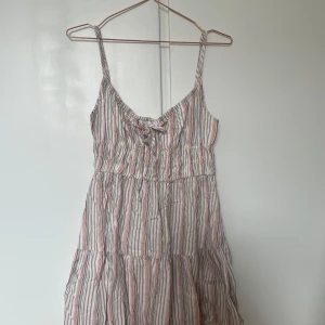 Randig klänning från Cotton On - Säljer en somrig randig klänning från Cotton On med smala axelband och en söt knytdetalj framtill. Klänningen har en fin passform och är perfekt för varma dagar🌼☀️