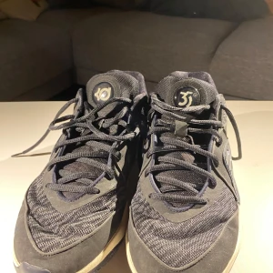 Svarta KD16 basketball skor med mönstrad sula - Snygga svarta sneakers med unik mönstrad sula och snörning. Perfekta för basketball. Skorna har en stilren design med diskreta detaljer.