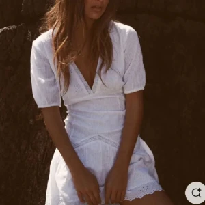 Vit klänning med spetsdetaljer - Säljer en söt vit kortklänning med v-ringning och spetsdetaljer. Klänningen har korta ärmar och en volangkant nedtill. Super populär & i mycket fint skick!!