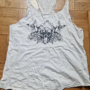 Säljer ett vitt linne från Wear It med ett coolt dödskalletryck i svart på framsidan. Strl L. Något sliten på sidan, annars fin, se bild. Katt i hemmet. 