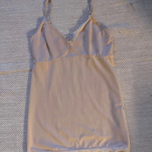 Ljusrosa linne/ nattlinne - Snyggt ljusrosa linne/ nattlinne med justerbara axelband och spetsdetaljer vid fållen. Perfekt för en stilren look. Klänningen har en v-ringad design och är tillverkad i ett mjukt material. Från Culture i storlek M