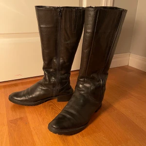 Svarta skinnstövlar  - Snygga svarta stövlar i skinn. De är fodrade med mjukt material för extra värme. Perfekta för kyligare dagar. Storlek 37, men passar även en 38a. Hör av er vid frågor!