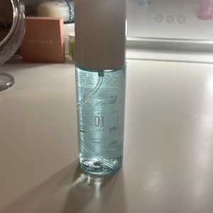 Parfym med blå flaska och vit kork - En elegant parfym i en genomskinlig blå flaska med vit kork. Flaskan har en stilren design och rymmer en doft som passar perfekt för den som söker något fräscht och uppfriskande. Perfekt att ha med sig i väskan för en snabb uppfräschning under dagen.
