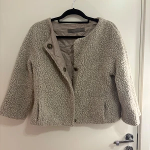 Trekvartsjacka  - Mysig beige trekvartsjacka i teddy material från Zara Basic med knappar framtill. Fin och gosig, storlek L men liten i storleken så passar mindre oxå, kort modell💕en knapp är sönder men går lätt att sy fast 