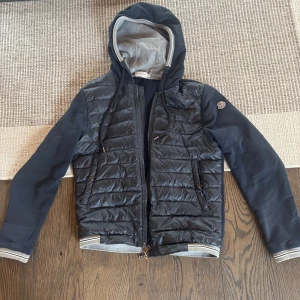 Moncler Cardigan M - As fet moncler cardigan i marinblå! 8/10 skick förutom lilla hålet på insidan som ses på bild 5. Syns inte eftersom det är på insidan, går att lappa ihop. Passar perfekt för dig som är 170-180 cm. Har kvitto från garmsmarket.se! Vid fler frågor kom dm!